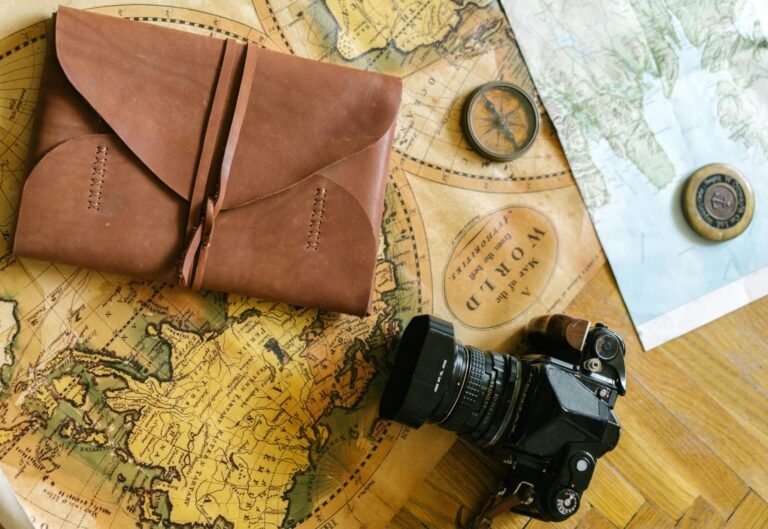 Flat lay of vintage travel items including a map, camera, and leather journal, perfect for wanderlust inspiration.